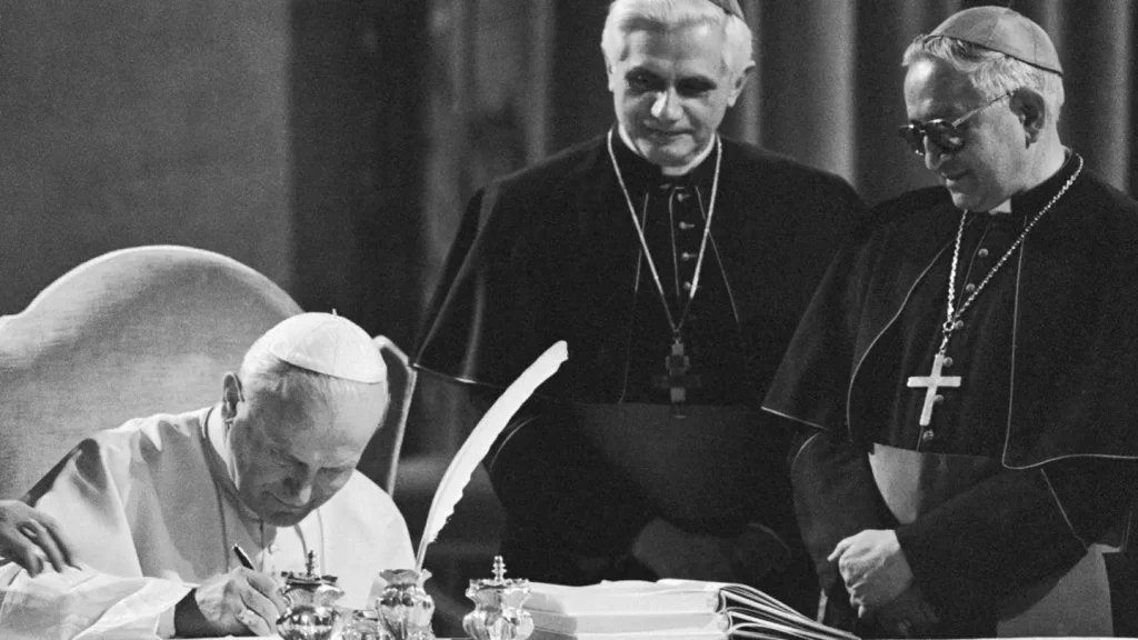 Pope John Paul II, seated at a table in the Old Consistorial Hall, signs the new Roman Catholic Code of Canon Law during a ceremony at the Vatican 1/25; in center West German Cardinal Joseph Ratzinger, and at right Venezuelan Archbishop Rosalio Jose Castillo Lara, Chairman of the Vatican commission that has been revising the code for the last two decades. The new Code of Canon Law is a more streamlined set of Church law that retains automatic excommunication for abortion and makes marriage annulments more complex. (Bettmann/Getty Images)